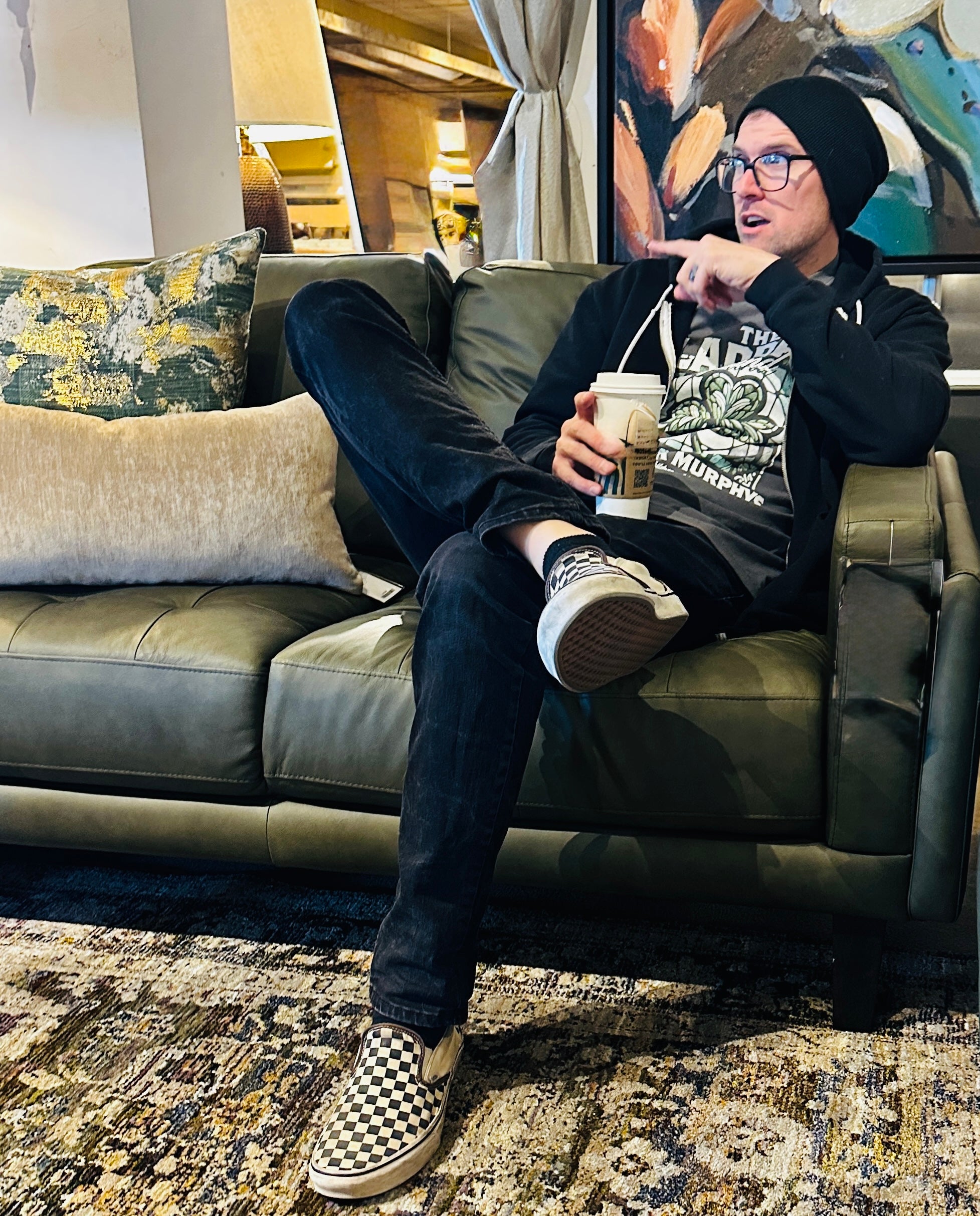 Person sitting on a couch holding a coffee cup in a living room setting