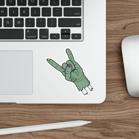 Laptop with a sticker of a green hand making a metal sign on a wooden desk.